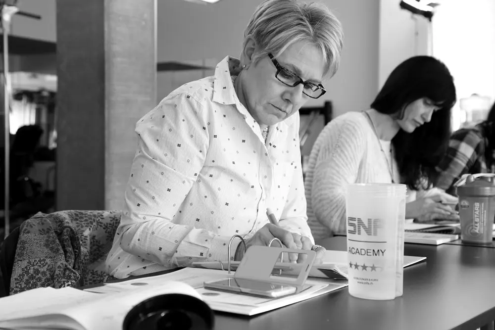 Professional woman taking detailed notes during AI coaching workshop on digital marketing and content strategy
